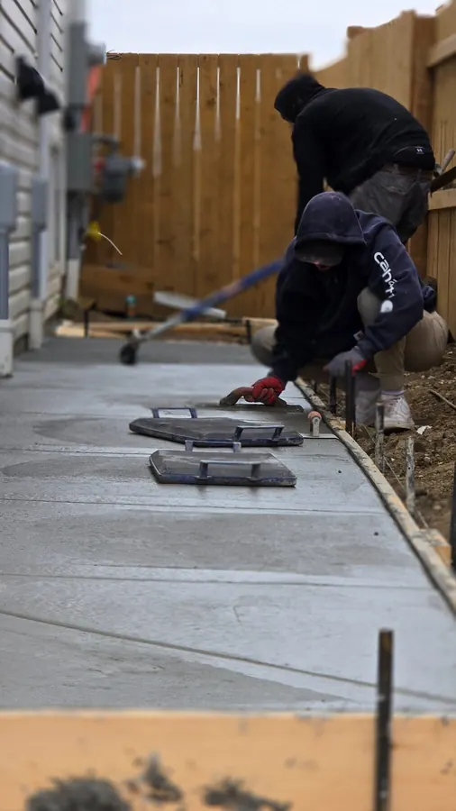 Close view of a worker beside a finished concrete surface and joint-detail area