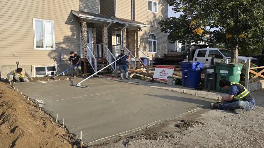 Fresh concrete driveway pour being levelled at a Saskatoon home