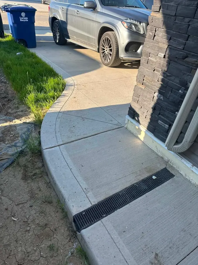 Concrete walkway with a grated channel drain beside a Saskatoon home